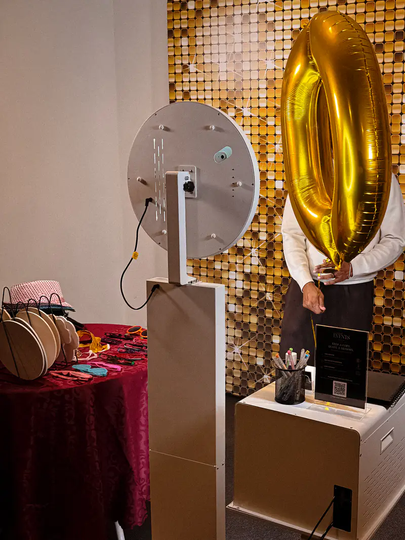 A guest hiding behind a gold number balloon at the booth