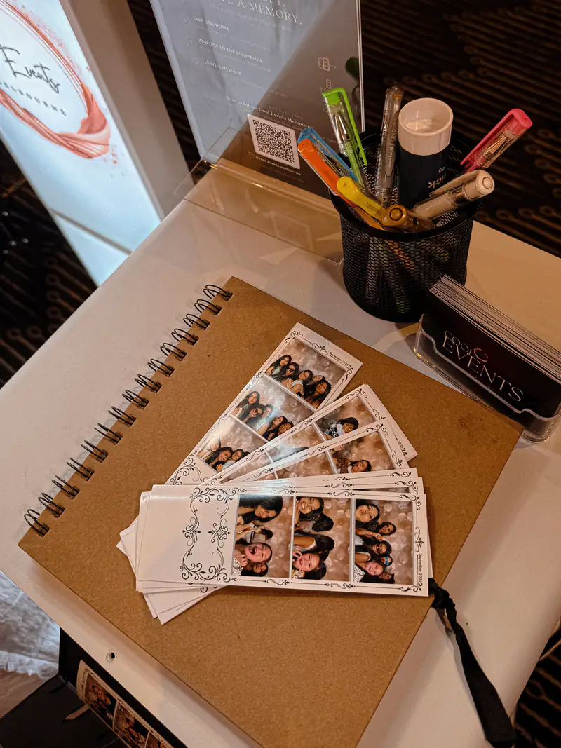A guestbook with photo strips and gel pens on the booth table